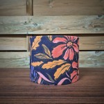 abat-jour cylindrique tissu fleuri aux motifs corail, rose et moutarde sur un fond violet profond